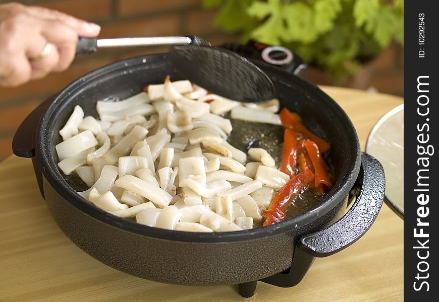 Woman cooking paella. This is the first step: Saut� the squids with the vegetables.