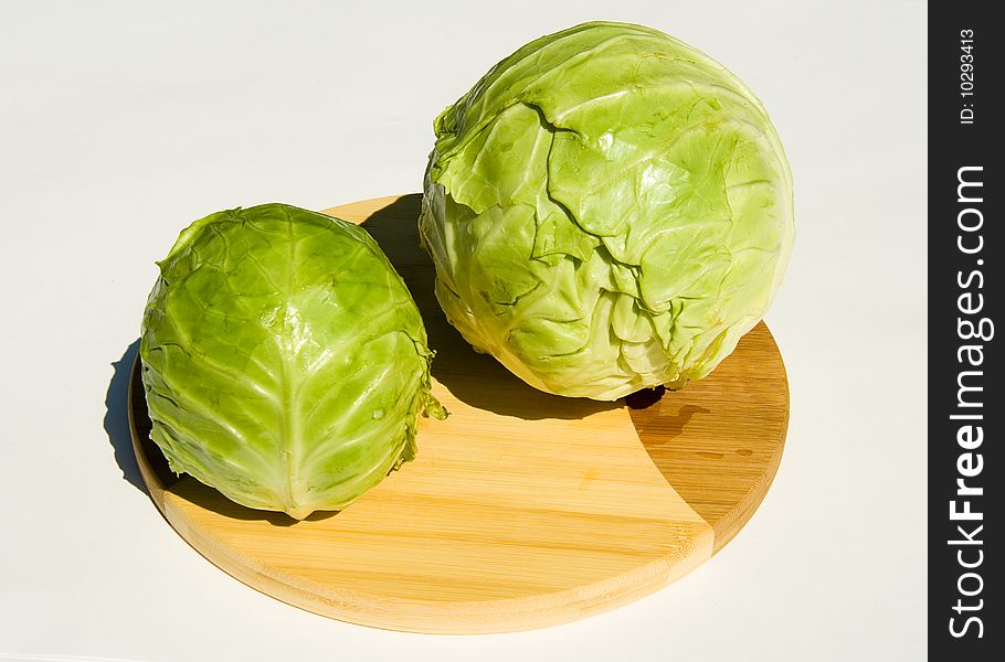 Two heads of cabbage on cutting board