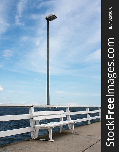 Wooden white bench at the sea coast with wonderful blue sky