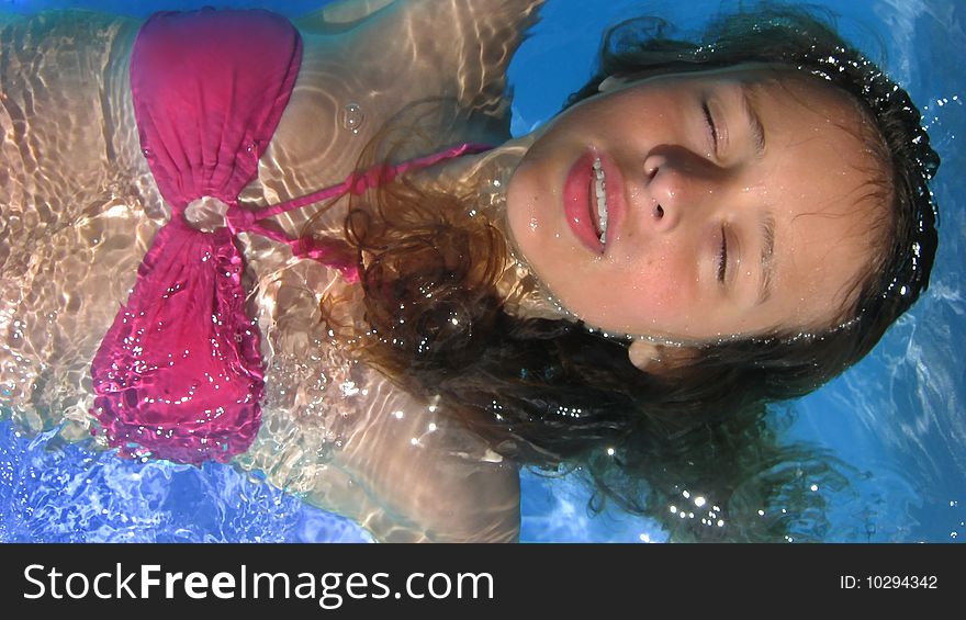 A young woman swimming on her back, drifting in a swimming pool. A young woman swimming on her back, drifting in a swimming pool.