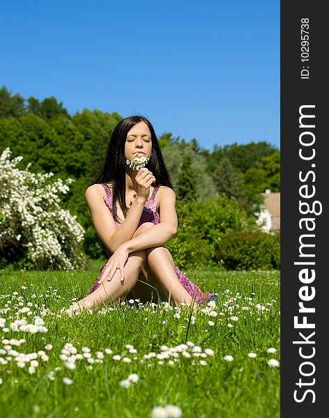 Beautiful young woman sitting on the grass with flowers. Beautiful young woman sitting on the grass with flowers