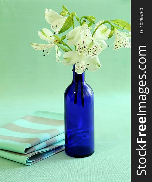 Blue bottle with flowers and napkin.