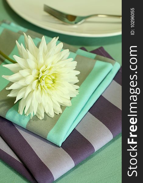 Plate, fork and white flower on napkin. Plate, fork and white flower on napkin.
