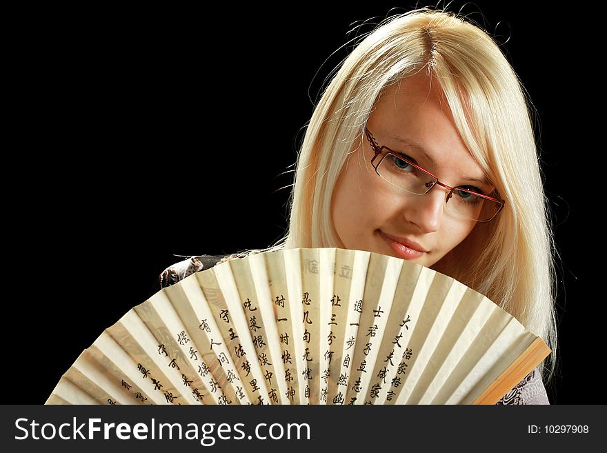 A young attractive woman with fan, isolated on black background