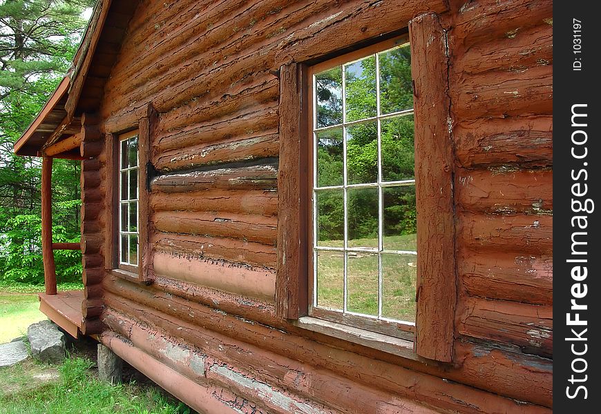 The windows of a log cabin reflecting the scenery. The windows of a log cabin reflecting the scenery