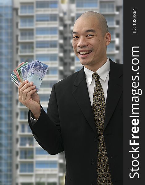 Chinese business man holding up money with building in the background. Chinese business man holding up money with building in the background