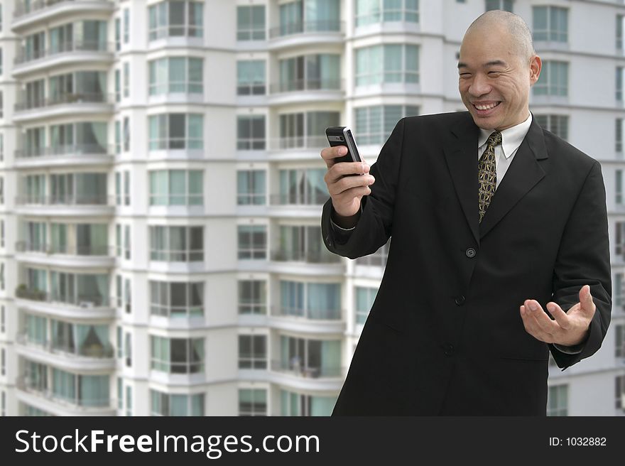 Chinese business man on a cellular phone with building in background. Chinese business man on a cellular phone with building in background