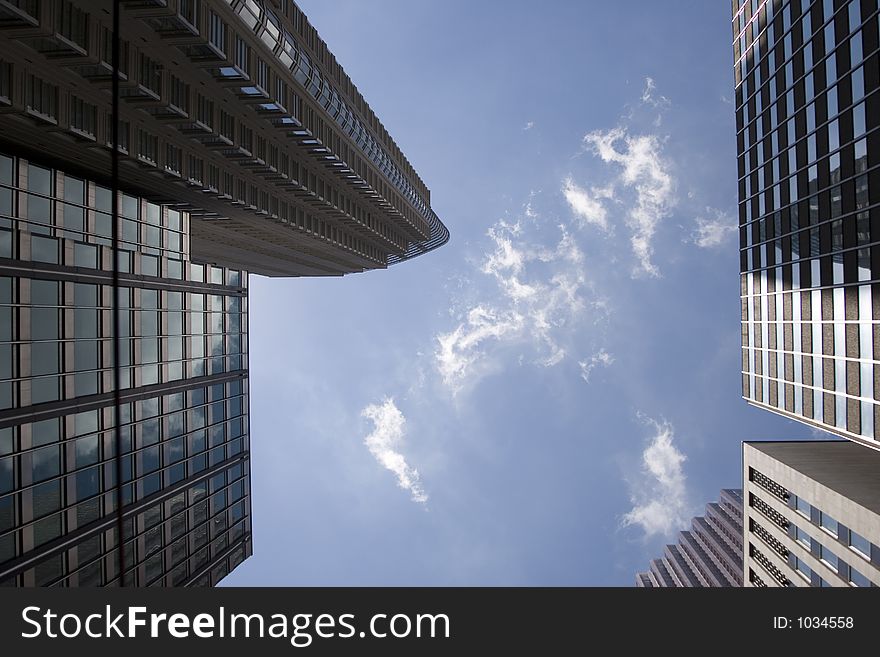 Picture taken from looking directly up into the sky between tall buildings. Picture taken from looking directly up into the sky between tall buildings