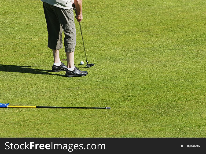 Golfer putting a short shot into the hole on a golfcourse. Golfer putting a short shot into the hole on a golfcourse