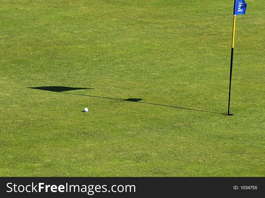 A putt going into the hole on a green on a golfcourse. A putt going into the hole on a green on a golfcourse