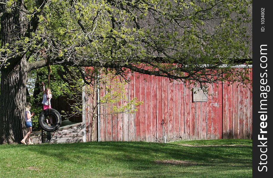 Two Girls Playing On A Tire Swing