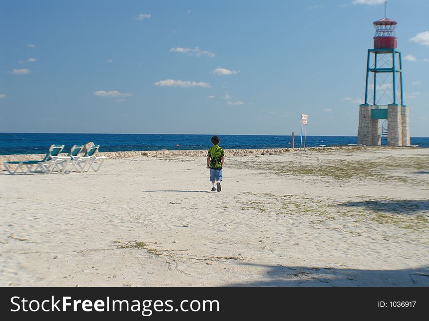 Boy walking on private beach with watch tower and empty beach chairs. Boy walking on private beach with watch tower and empty beach chairs