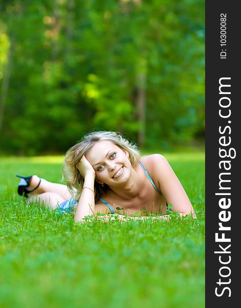 Beauty young woman lying on a green grass