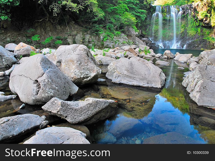 Low shot of majestic waterfall with huge rocks in the foreground