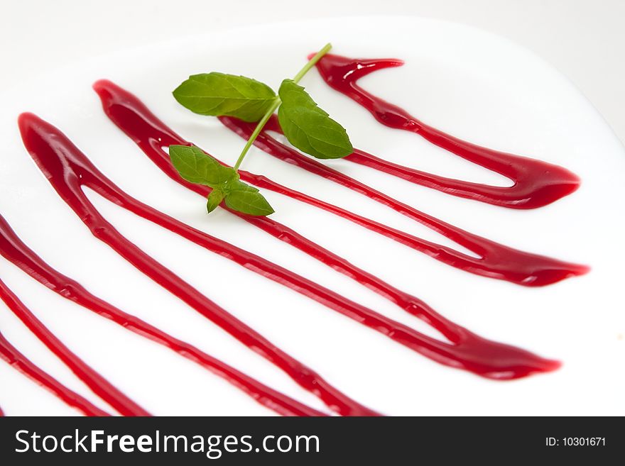 Elegant white plate decorated with cherry sauce and mint
