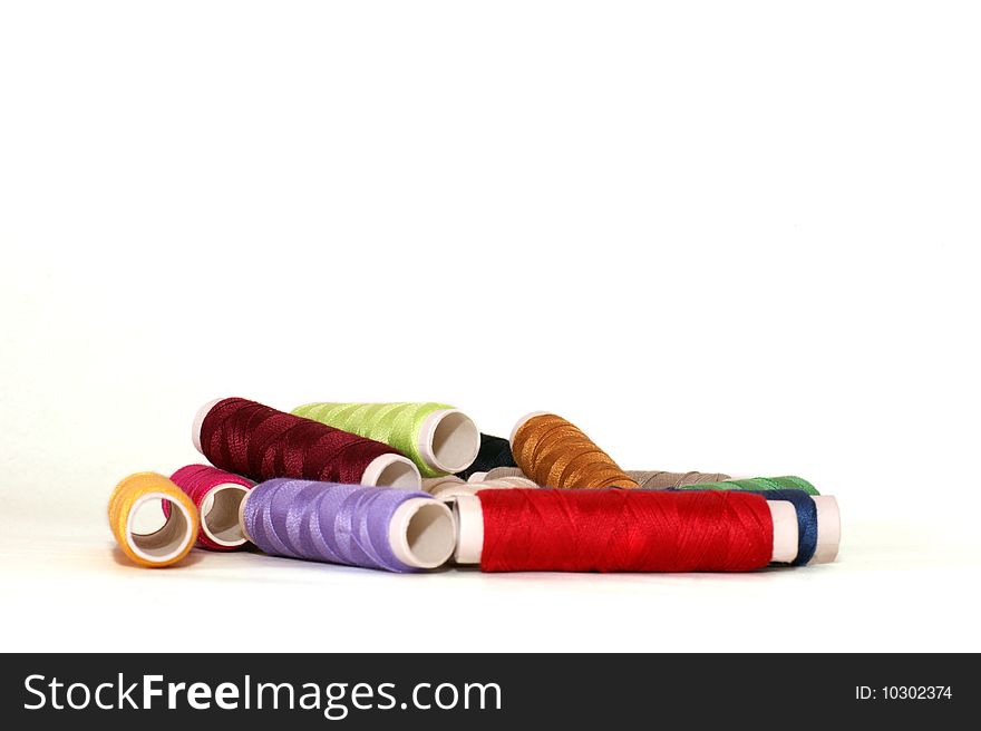 Sewing thread in different colours on a white background