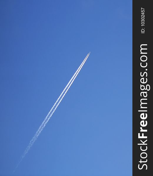 Contrail of a jet airliner high in a clear blue sky