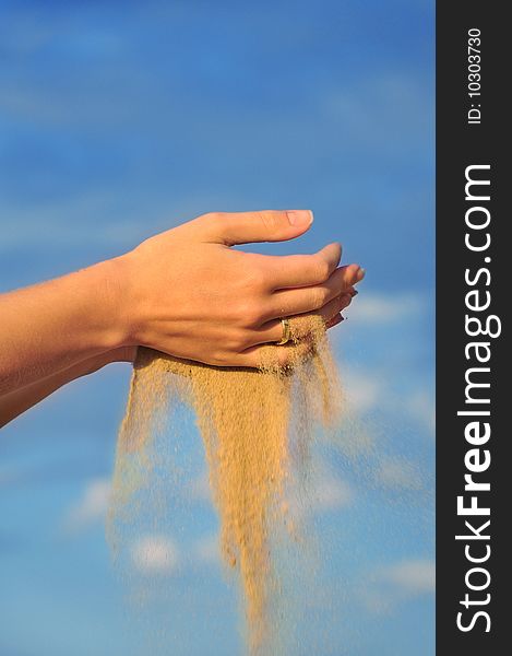 Sand falling through his hands against the backdrop of the sky. Sand falling through his hands against the backdrop of the sky