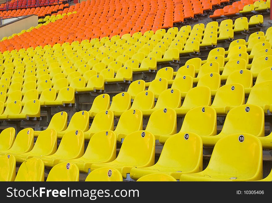 Rows of yellow, red and orange seats on the stadium with fences around the edges of the sectors