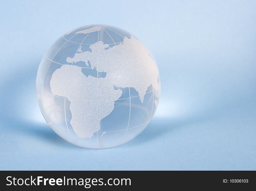 World from glass on blue background