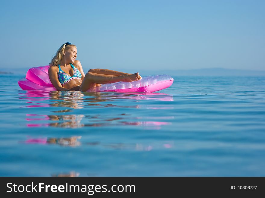 Beautiful blonde girl floating on inflatable raft in the sea. Beautiful blonde girl floating on inflatable raft in the sea