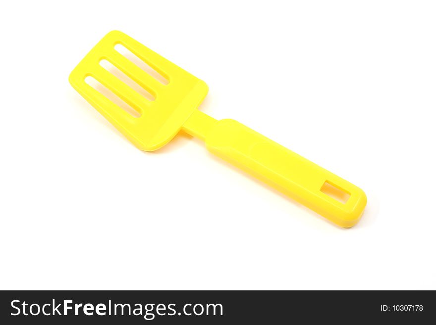 A yellow toy spatula on a white background.