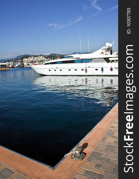 A beautiful yacht moored at a dock reflected in the water of the port of Genoa. A beautiful yacht moored at a dock reflected in the water of the port of Genoa