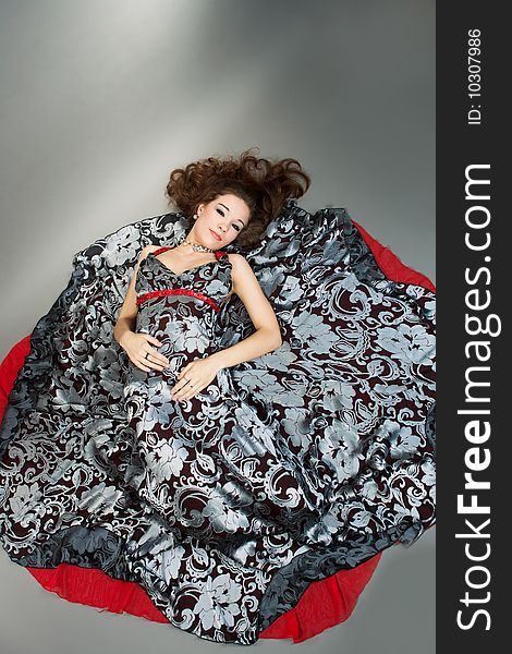 Young woman on floor on color dress separated on gray