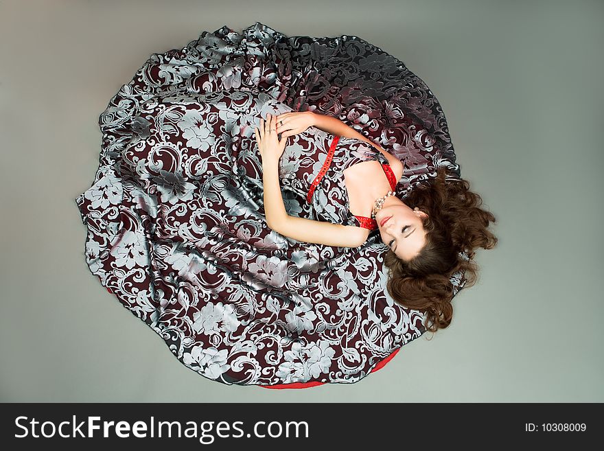 Extravagant young lady on color dress laying on floor with eyes closed separated