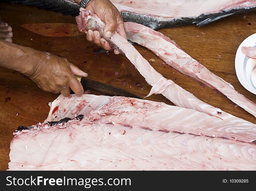 A big fish is being cleaned and cut up by a fisherman.  The meat is being cut up into slices for sale. A big fish is being cleaned and cut up by a fisherman.  The meat is being cut up into slices for sale.