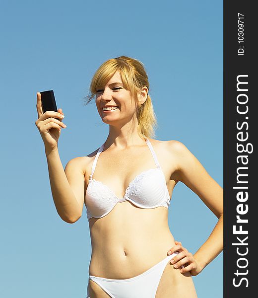 The beautiful girl on a beach calls by a mobile phone. The beautiful girl on a beach calls by a mobile phone
