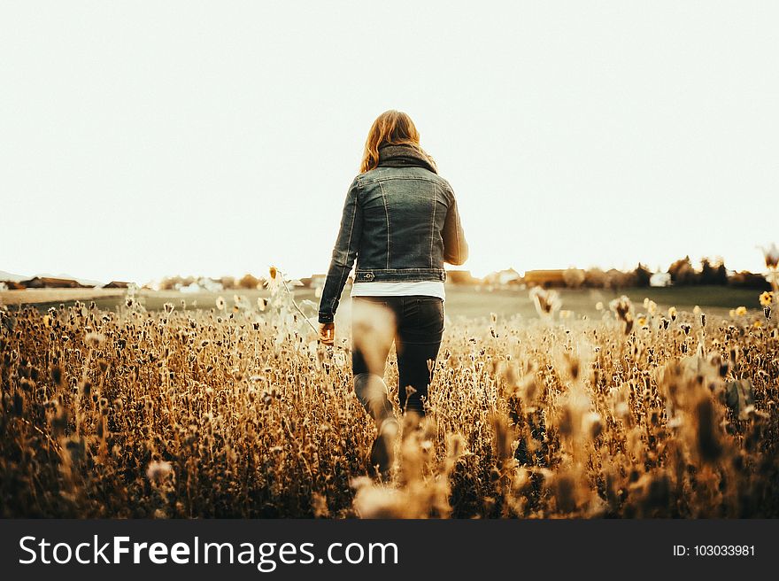 Woman in Blue Denim Jacket Walking on Field