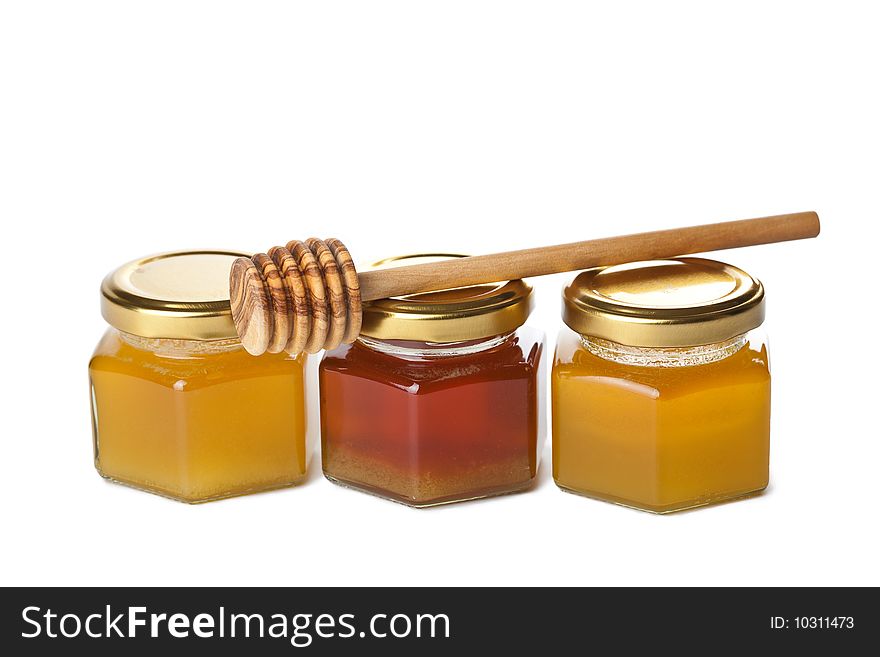 Honey in bottles and wooden dipper isolated over white