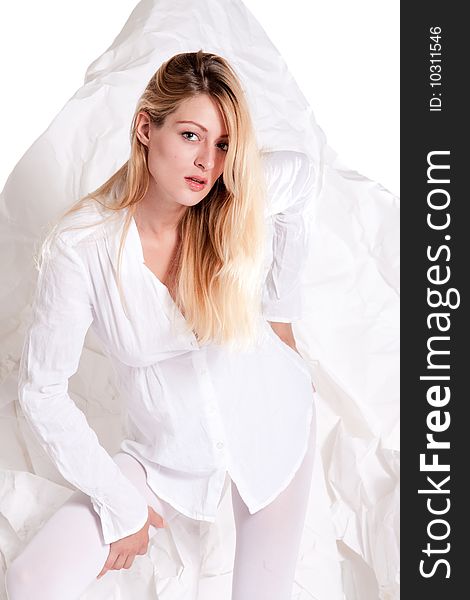 Beautiful blond young woman posing in white studio dressed in high fashion white. Beautiful blond young woman posing in white studio dressed in high fashion white