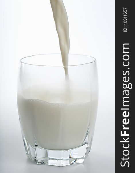 Fresh milk pouring into glass isolated