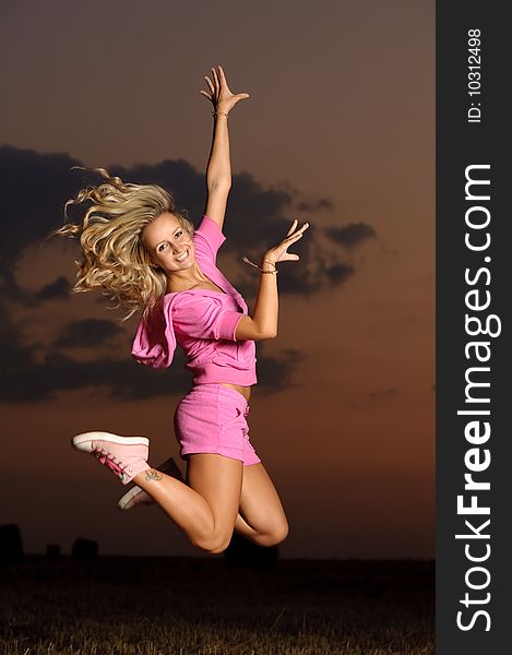 Blond girl outdoor jumping at evening time