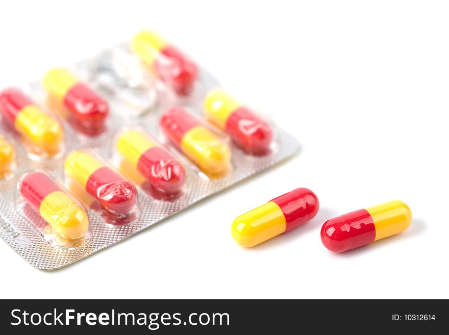 Red and yellow capsule pills in blister isolated over white