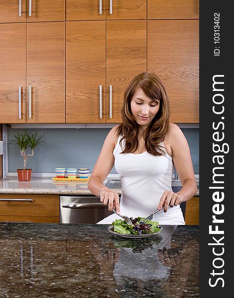 Woman eating a salad in a modern kitchen