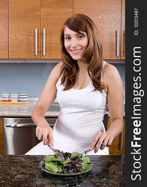 Woman eating a salad in a modern kitchen