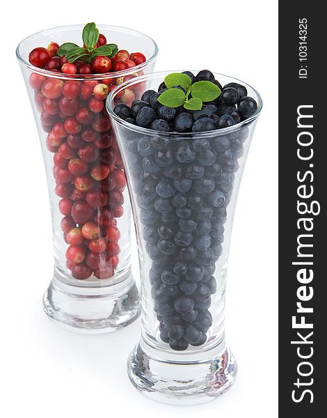 Cranberries and bilberries in glass on white background. Cranberries and bilberries in glass on white background.