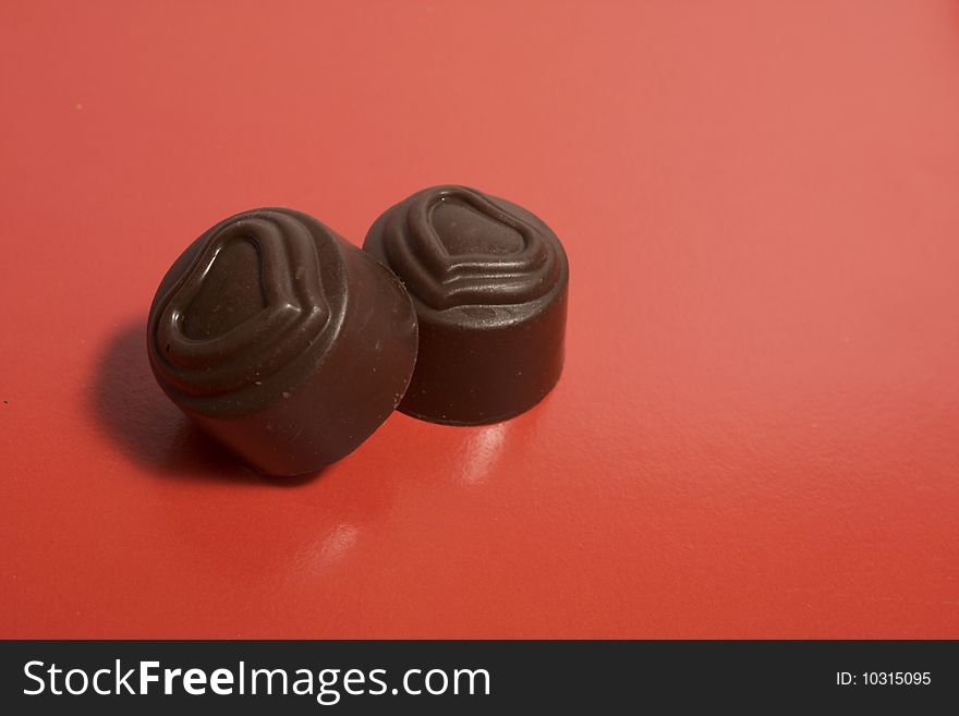 Pair of chocolate sweets with the image of heart on a red background