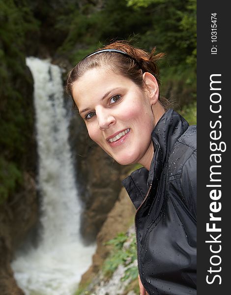 Young woman is hiking. In the background you can see a waterfall. The focus is on the woman. Young woman is hiking. In the background you can see a waterfall. The focus is on the woman.