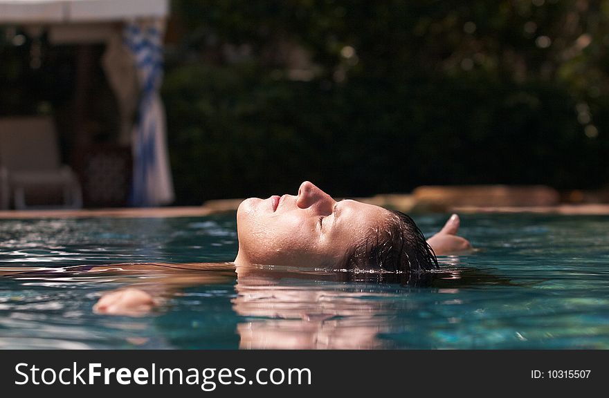 Young woman in a beautiful pool with palms in the background. Young woman in a beautiful pool with palms in the background.
