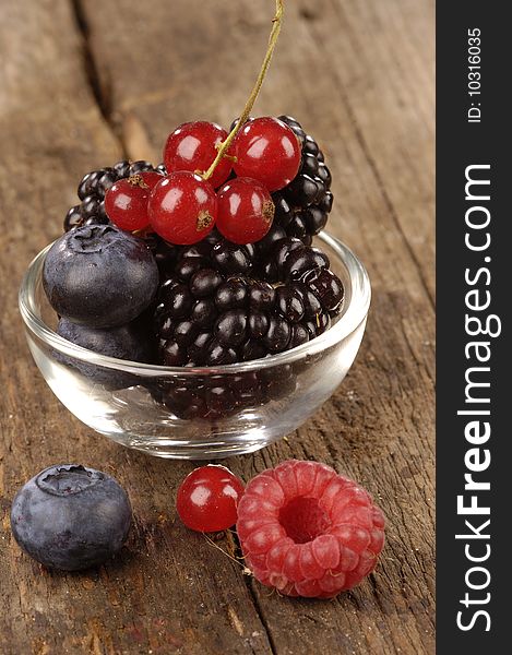 Fresh berries in a glass bowl  on a wooden table. Fresh berries in a glass bowl  on a wooden table