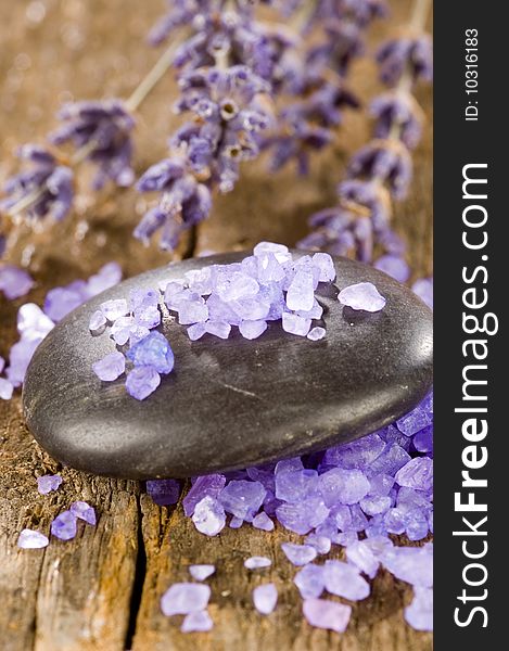Black spa stones with salt and lavender on a wooden table
