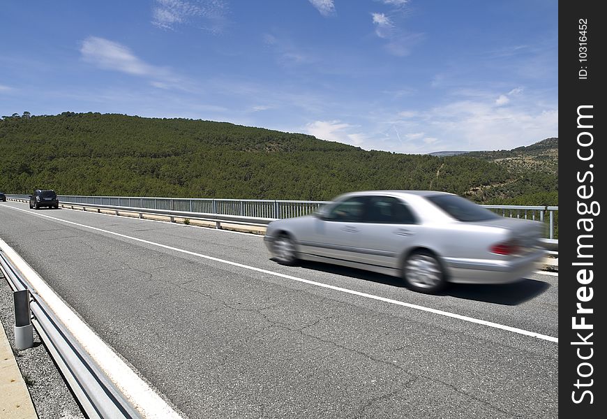 Road scene of several cars in a mountain road. A bridge over the cofio river in Spain. Road scene of several cars in a mountain road. A bridge over the cofio river in Spain.