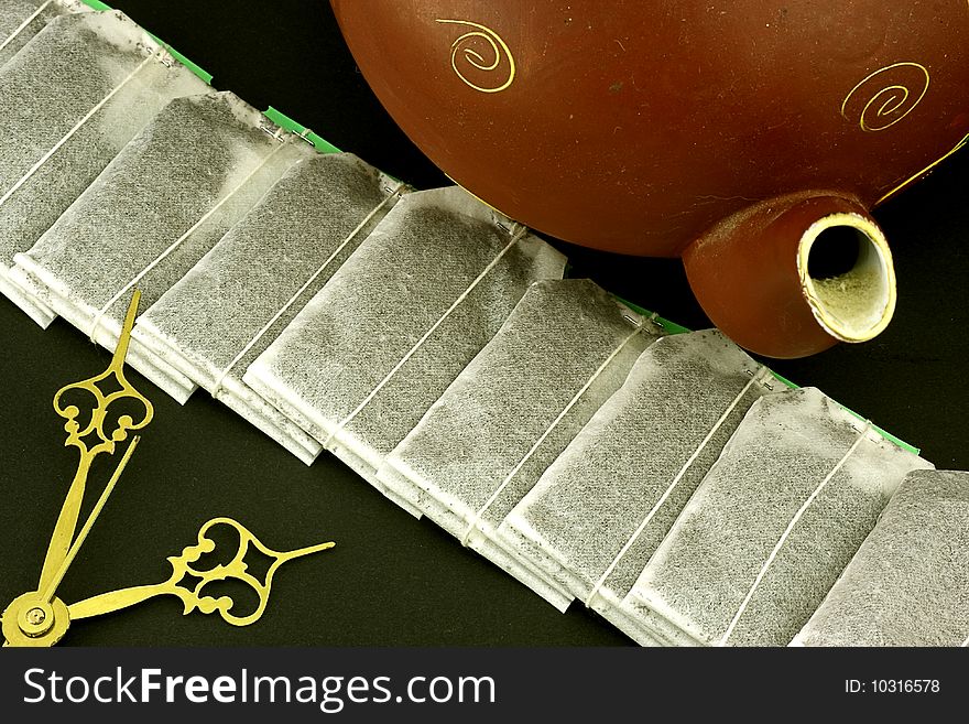 A tea time still life showing teabags teapot and clock hands. A tea time still life showing teabags teapot and clock hands