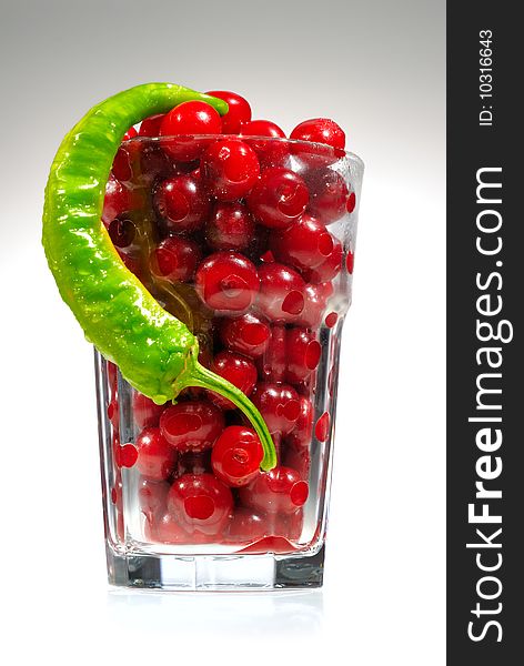 Juicy, big and sweet cherries and pepper in high glass on white background