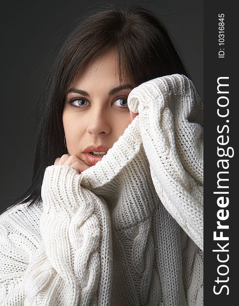 Portrait of a beautiful young brunette woman wearing a white oversized jersey on black background. Portrait of a beautiful young brunette woman wearing a white oversized jersey on black background