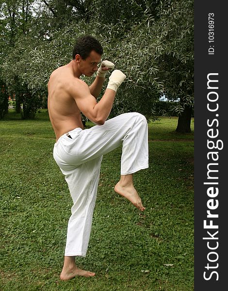 Fighting man practicing his skills outdoor in a park